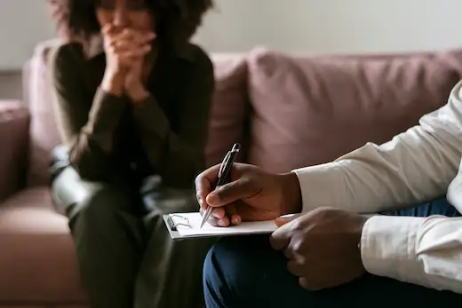 Formation gestion du stress au travail : accompagnement individuel bienveillant entre un professionnel prenant des notes et une personne en situation de mal-être