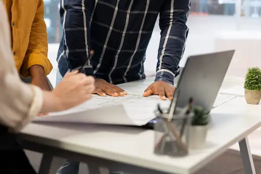 Formation manager en contexte incertain : collaborateurs analysant des plans et documents stratégiques ensemble, illustrant la prise de décision et l'adaptation face à l'incertitude