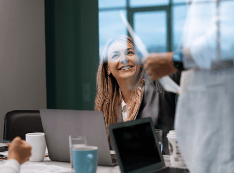 Salariée souriante en réunion illustrant l'amélioration de la qualité de vie et de l'engagement au travail