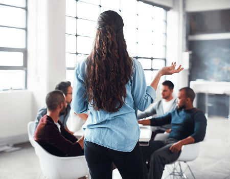 Coach animant une session de coaching collectif auprès de dirigeants et d'équipes en entreprise