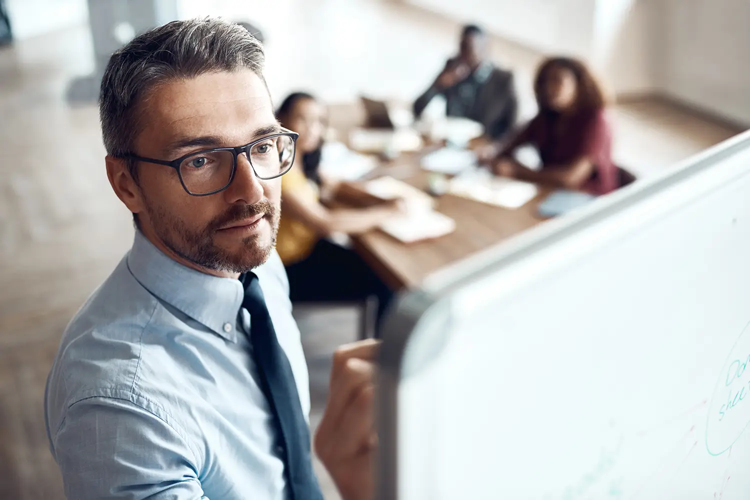 Coach professionnel certifié animant une session de coaching en entreprise avec une équipe de collaborateurs en réunion