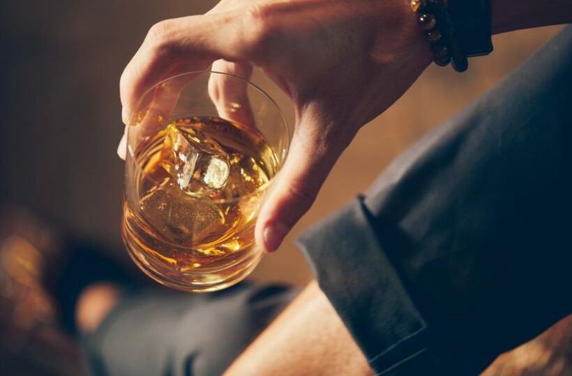 A high angle closeup shot of a male holding a glass of whiskey